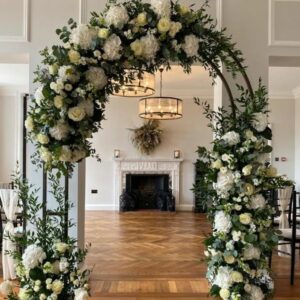 Wedding arch filled with beautiful white flowers framing a fireplace