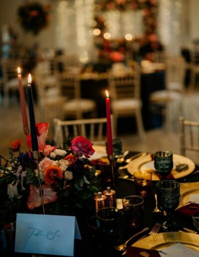 Image of Gellifawr Woodland Retreat function room dressed for Ryan and Darcie's wedding - the background is blurred and in focus are table centres with red lit candles and a table number
