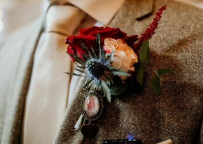 Ryan's buttonhole made of red and white roses, a thistle and a photo of his Dad, Darren in a locket